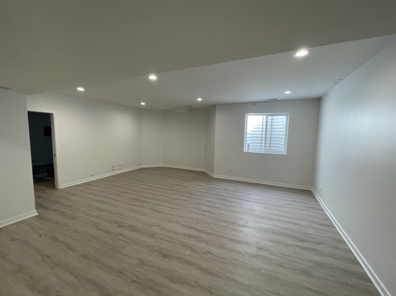 Basement remodel with LVT flooring, white walls, and recessed lighting