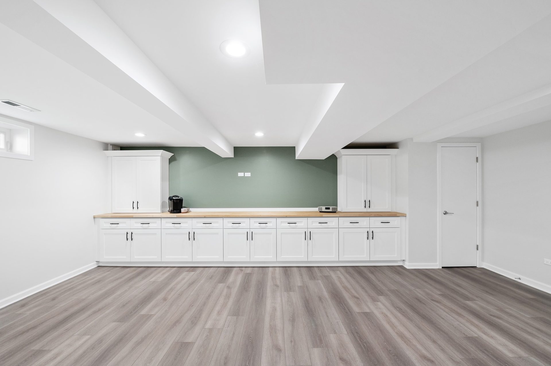 Full basement remodel with LVT flooring, white cabinets with black hardware and butcher block countertop