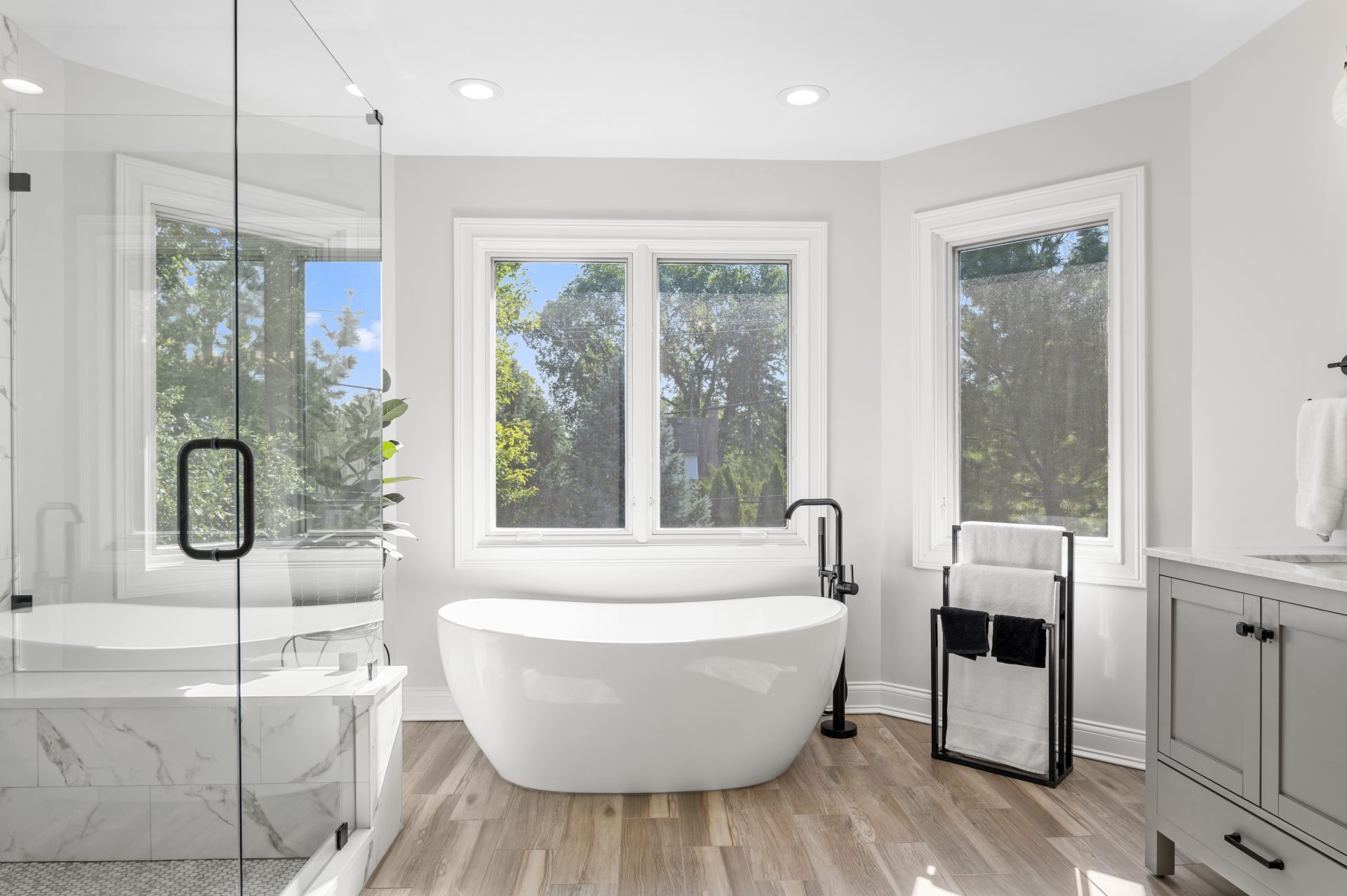 Master bathroom remodel with freestanding tub, tiles that look like hardwood, walk-in shower, custom shower glass, marble look alike tile, and floor mosaic penny tiles