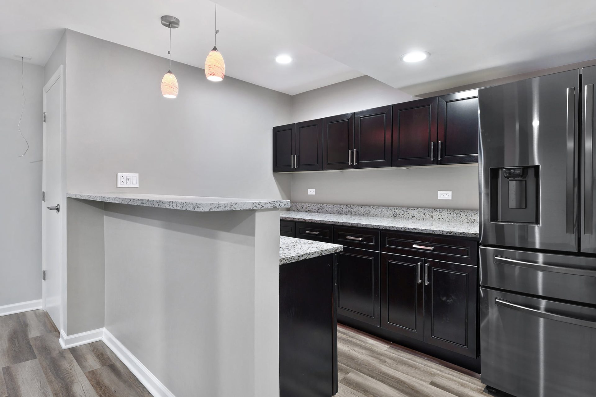 Full basement remodel with dry bar, LVT flooring, can lights, cabinets for dry bar, quartz countertop, stainless steel appliances, pendants for bar area, and chrome handles