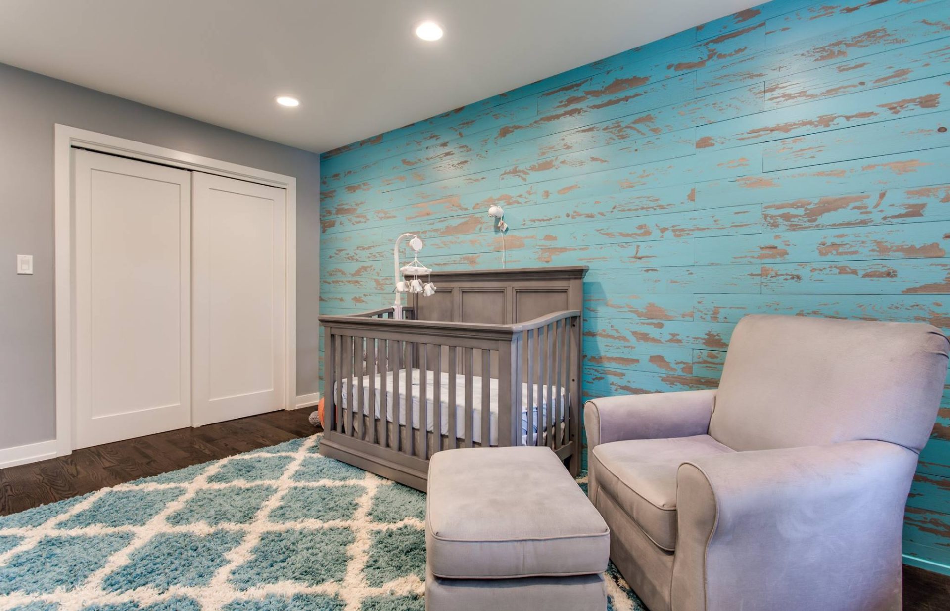 Remodeled nursery with new closet door, new windows, new flooring, and distressed blue wood shiplap decorative wall