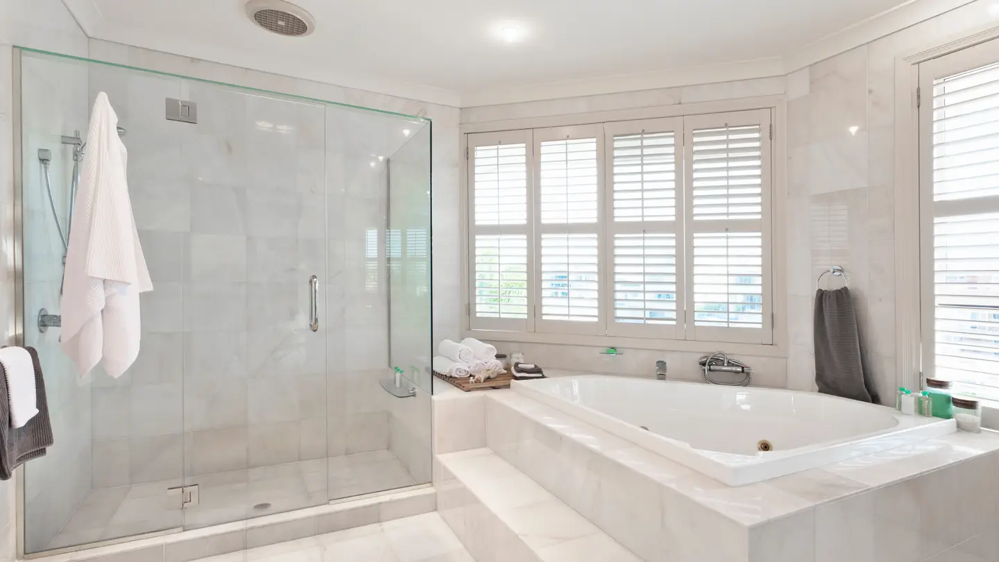 Large all-white bathroom with a large white walk-in shower and a large white tub.