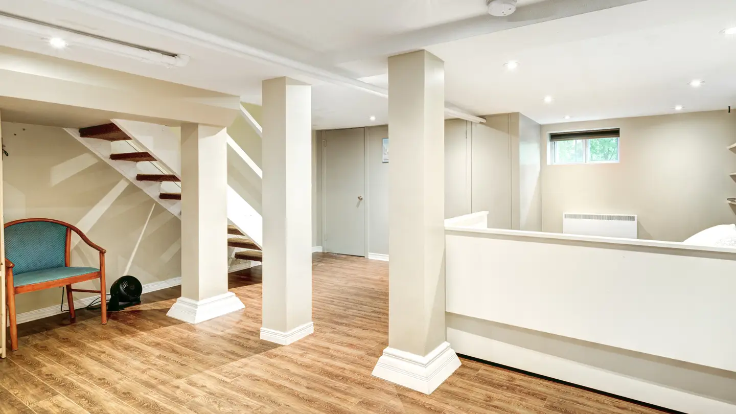 Large basement with white walls and white pillars and new finishes wood flooring