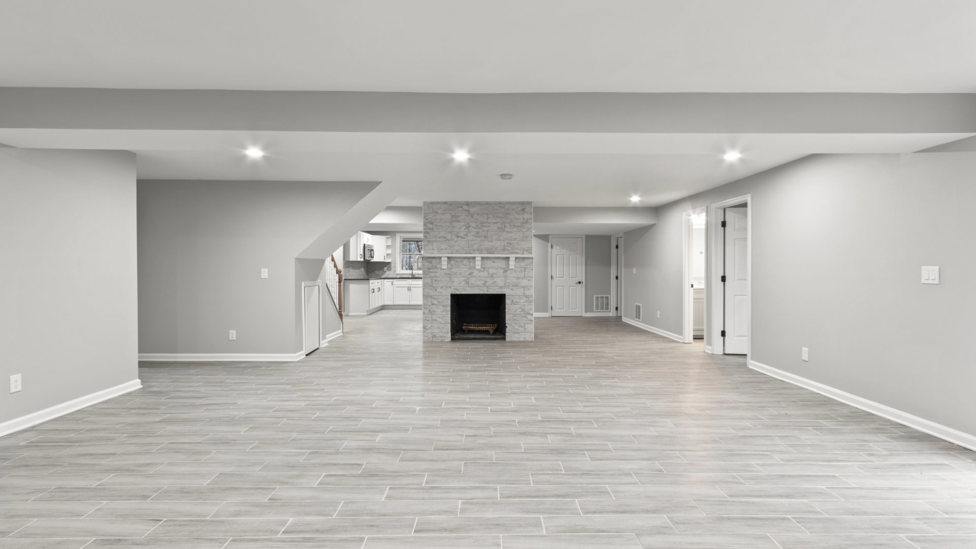 A large basement remodel with gray walls and gray flooring 