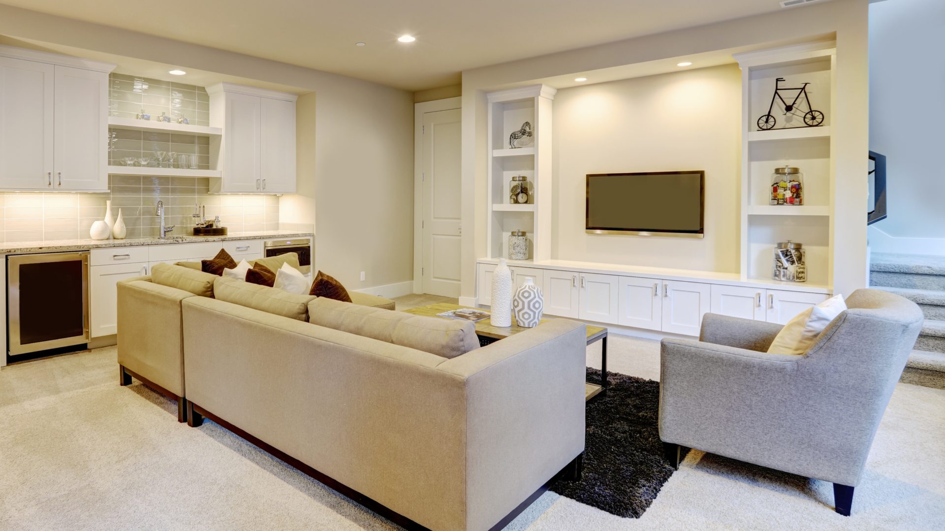 A basement with white walls and a white couch that has a built-in wall with a tv