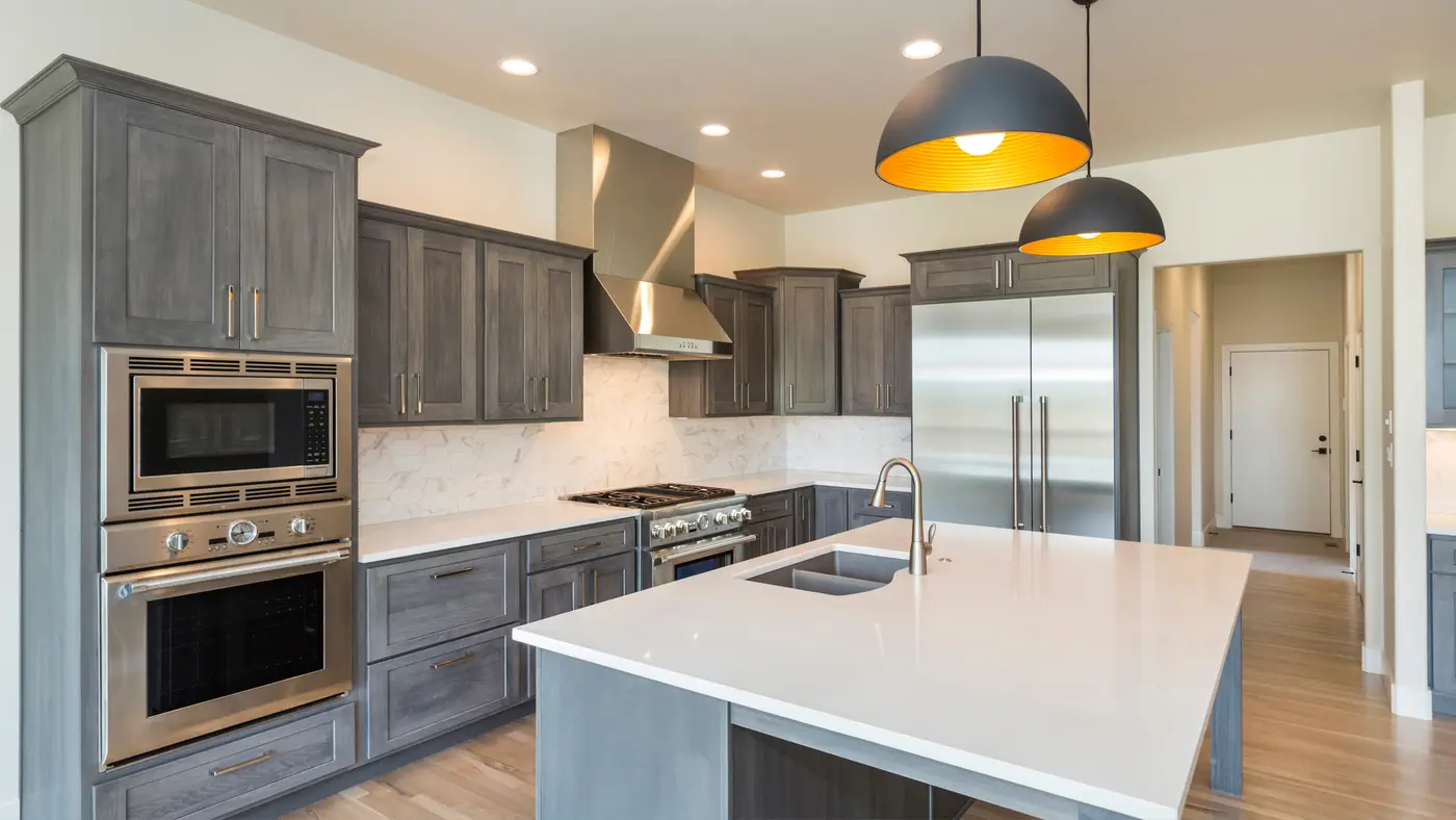 A kitchen with gray cabinets and an island with a white countertop