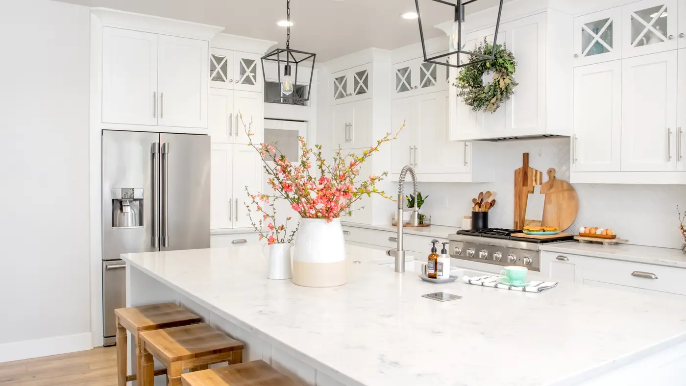 A kitchen with white countertops and white cabinets with silver appliances 