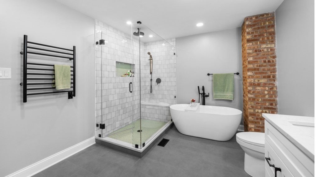 New bathroom remodeling project in Oak Park, IL by 4Ever Remodeling with new white bathtub, gray tile flooring, and modern glass shower unit