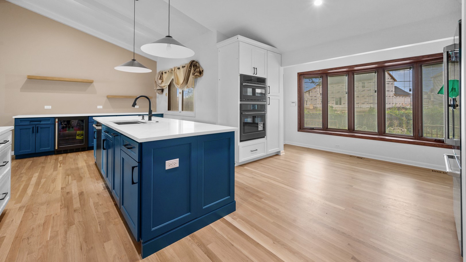 Oak Park, IL kitchen with bright wood flooring, blue cabinets, and beautiful large windows with dark wooden frames