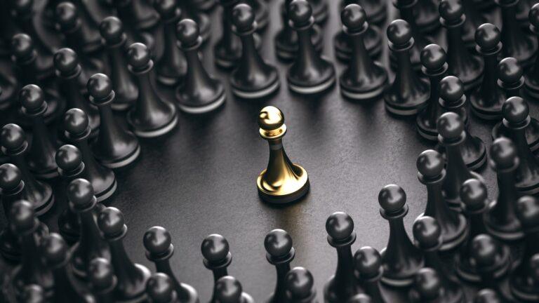 3D illustration of black pawns around a golden one standing out from the crowd. Concept of leadership