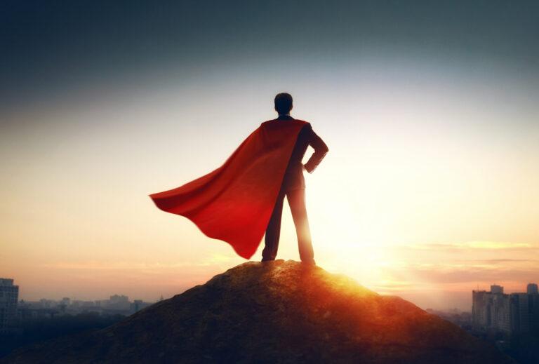 superhero businessman looking at city skyline at sunset. the concept of success, leadership and victory in business.
