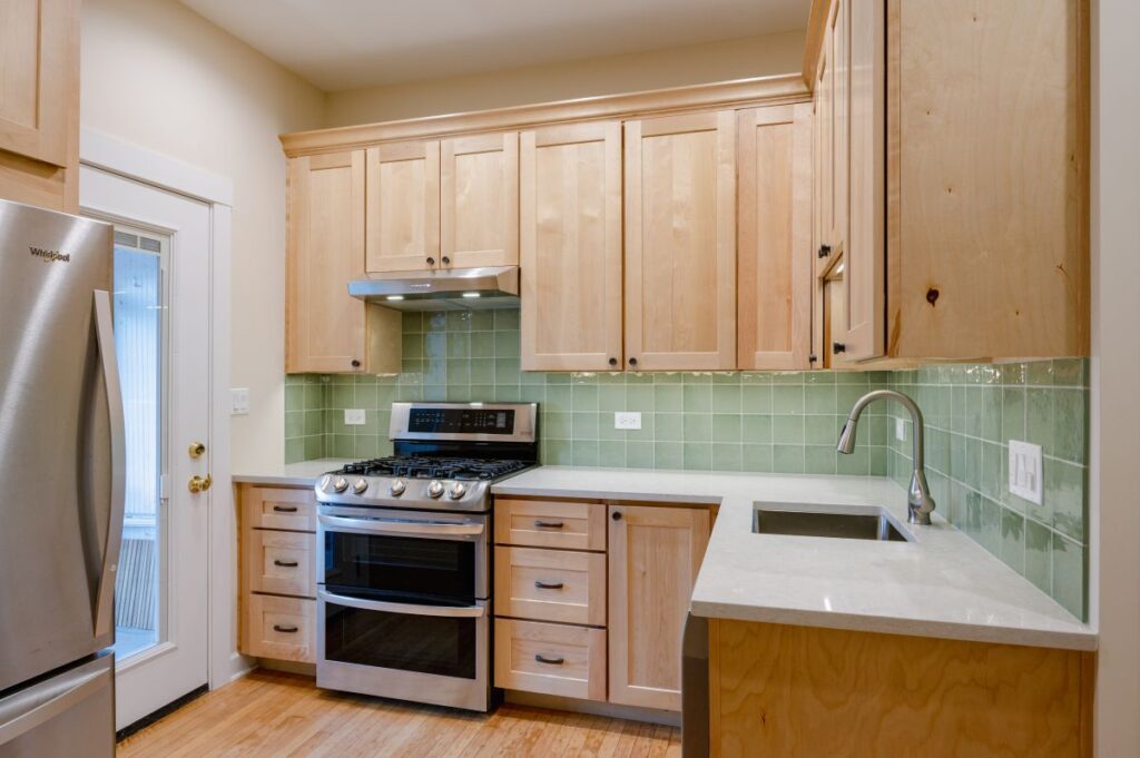 Kitchen with light green back splash and wooden cabinets