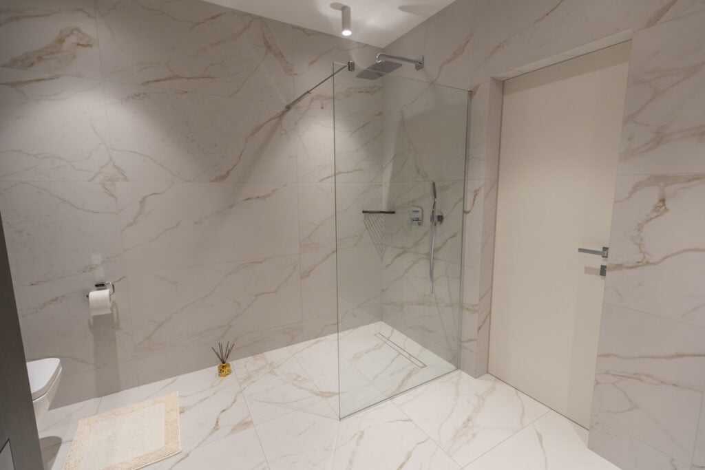 white marble master bathroom with large glass walk-in shower,