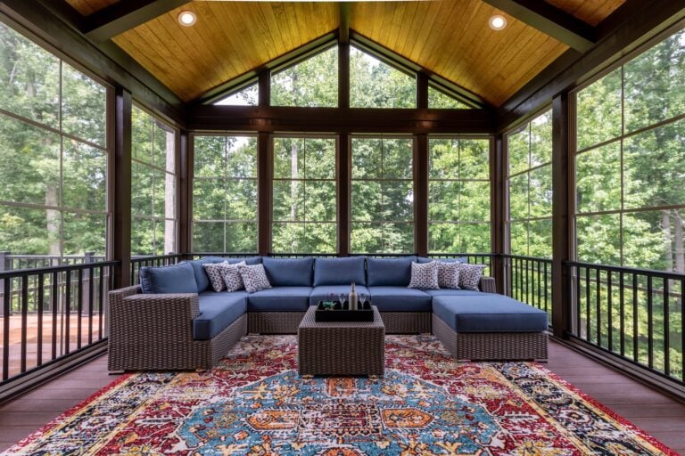 New modern screened porch with patio furniture, summertime woods in the background.