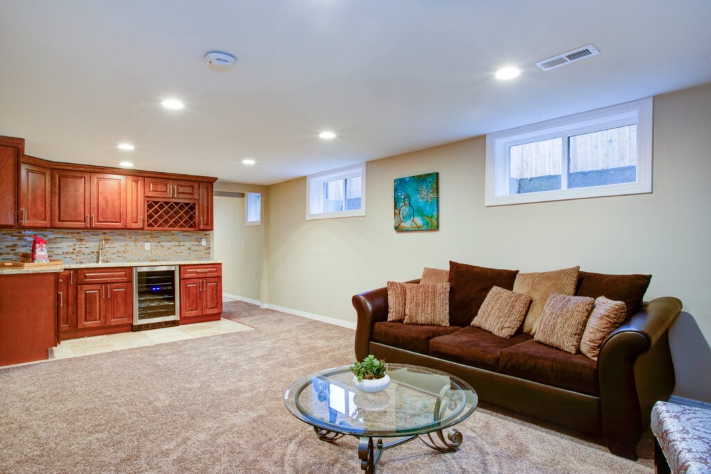 wet bar ideas for basement sofa and small table Stunning basement interior boasts a nice wet bar composed of wood shaker cabinets with granite countertop and a mosaic backsplash.