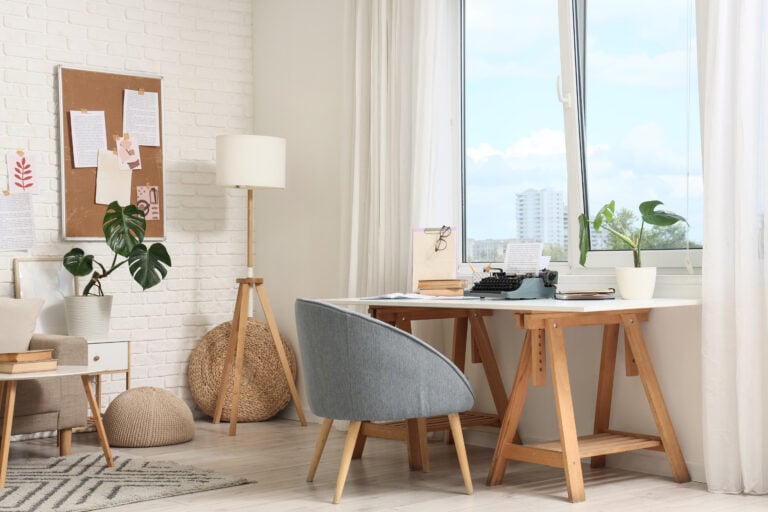 Home office interior with a vintage typewriter on a wooden desk and a monstera plant by the window, a monstera plant in a white pot sits on the windowsill, adding a touch of greenery to the workspace